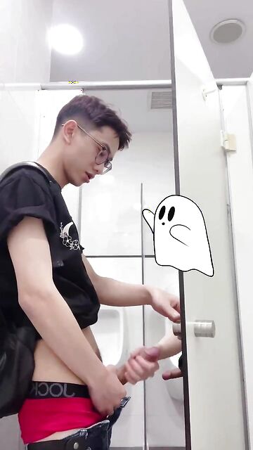 Asian twink dude being jerked by his friend in a public toilet stall